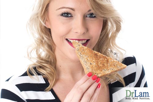Young woman smiling and eating a slice of toasted bread. Making sure the foods you eat play well together is key to the food combining diet.