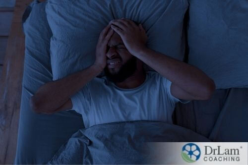 An image of a man laying in bed at night, struggling to sleep