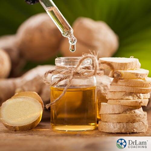An image of sliced ginger next to a bottle of essential oil
