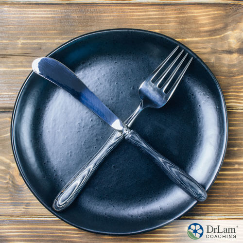 An image of an black plate with a fork and knife crossing each other on it