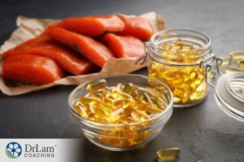 An image of fish oil gel caps with sliced salmon in the background