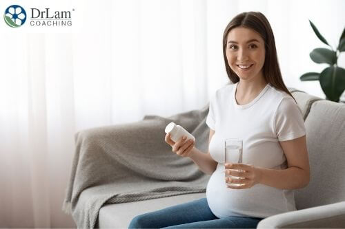 An image of a pregnant woman holding a bottle of supplements and a glass of water