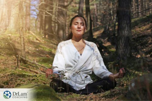 An image of a woman meditating in the forest