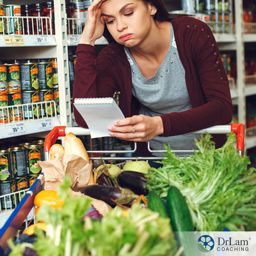 An image of a young woman exhausted in the grocery store looking at her list