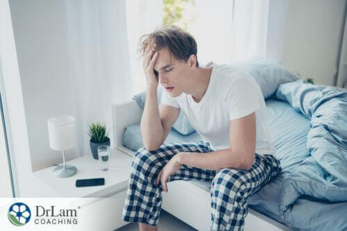 An image of a fatigued man sitting on a bed
