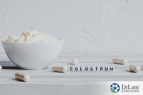 An image of a bowl containing powdered colostrum with capsules and the word colostrum spelled out next to it