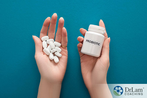 An image of a woman's hands holding a bottle of probiotics and some of the tablets