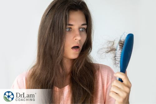 An image of a woman looking at her brush full of her hair