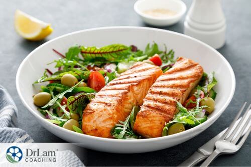 An image of a salad with grilled salmon on it