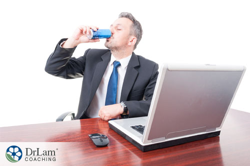 An image of a businessman drinking too many heart threatening energy drinks