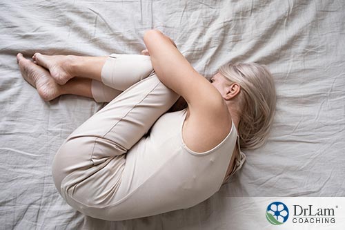 An image of a woman laying on the bed curled up into a ball