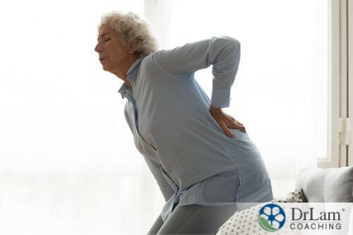 An image of an older woman holding her lower back in pain