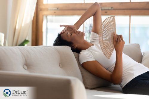 An image of a woman laying on the couch with a fan in her hand