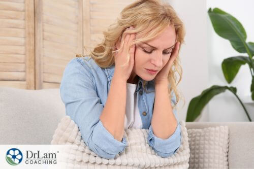 An image of a woman holding her head while sitting on a couch