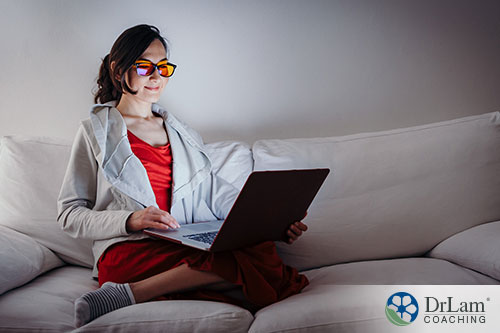 An image of a young woman on her laptop sitting on the couch