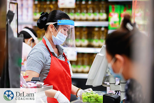 An image of a grocery clerk wearing personal protective equipment while she works
