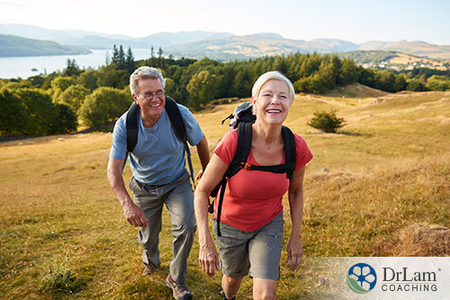 An image of an older couple hiking up a hill and smiling