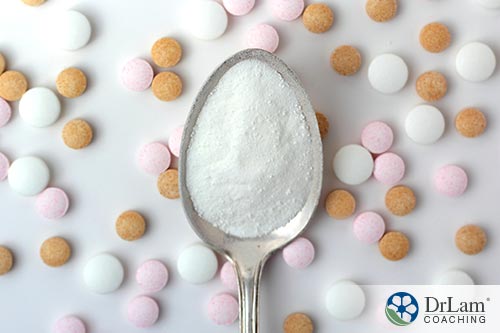 An image of white powder in a spoon with different colors of tablets in the background