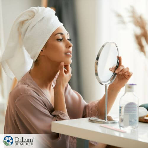 An image of a woman looking at her face in the mirror