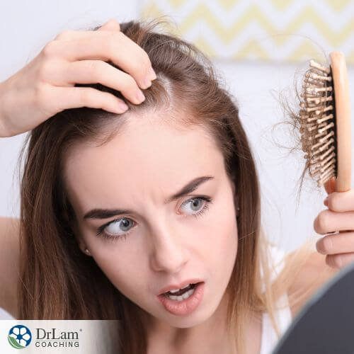 An image of a woman brushing her hair and seeing it falling out