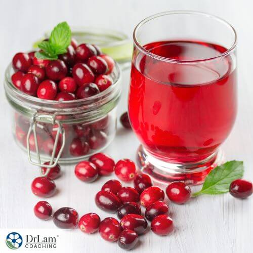An image of cranberries in a jar and a glass of cranberry juice