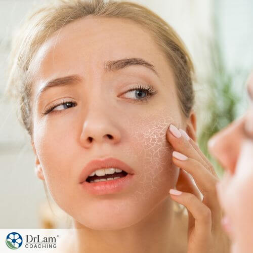 An image of a woman looking at her face with dry skin on it