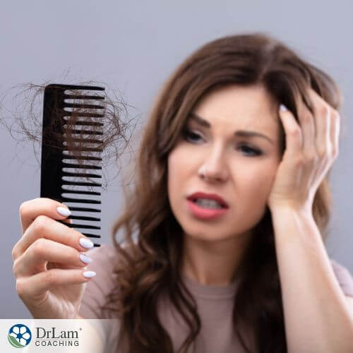 An image of a woman looking at a comb filled with her hair