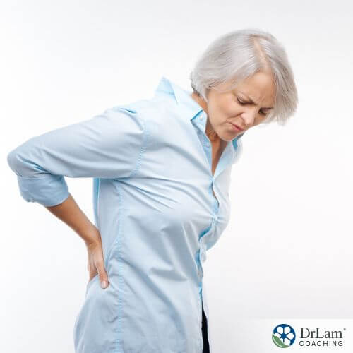 An image of an older woman holding her lower back in pain