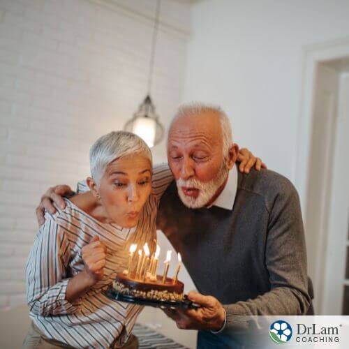 An image of an older couple blowing out candles on a cake together