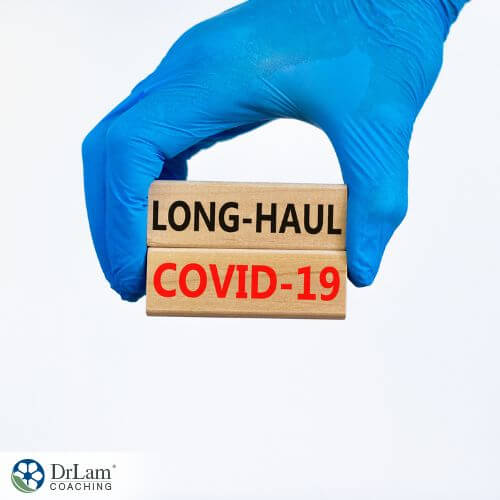 An image of a hand holding a sign saying Long-Haul COVID