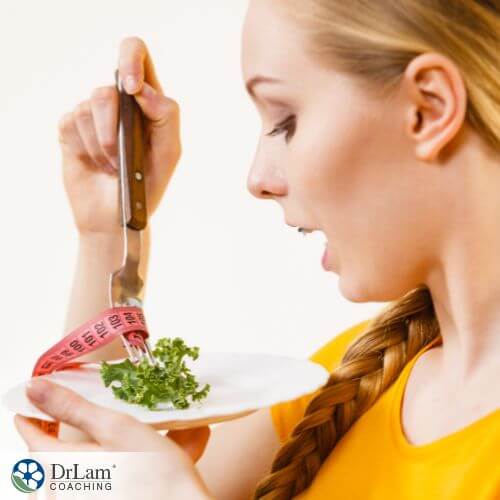 An image of a woman holding a plate with one lettuce leaf on it and a tape measurer around the fork