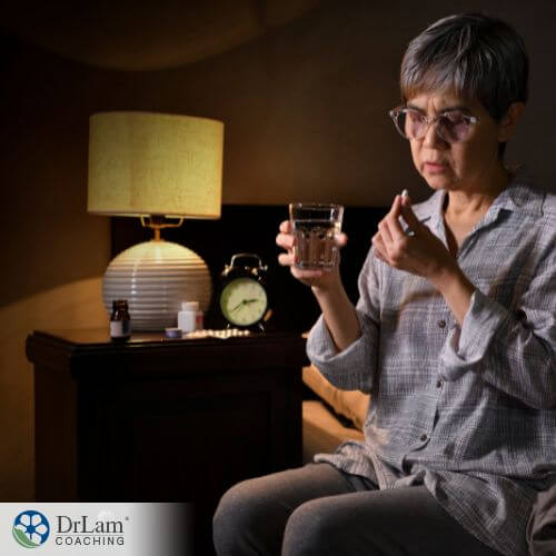 An image of a woman sitting on her bed holding a pill and glass of water