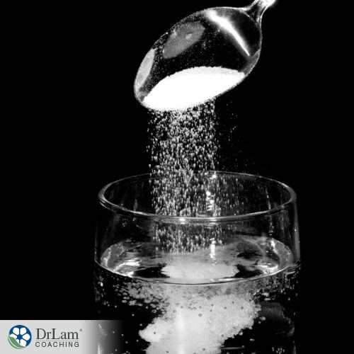 An image of someone adding salt to a glass of water