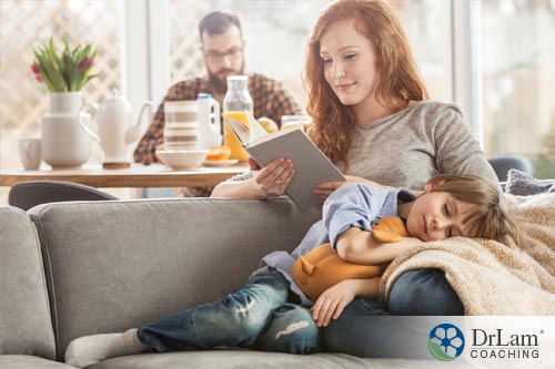A woman reading on the couch cuddling a small child practicing intuitive eating