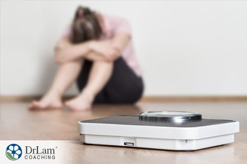 An image of a scale in the forefront with a woman in the background who is frustrated with dieting instead of practicing intuitive eating