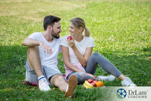 An image of a couple in the grass practicing intuitive eating with healthy fruit