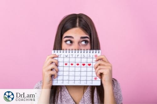 An image of a woman holding a calendar marked with her menstrual cycle days