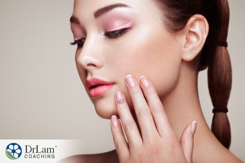 An image of a woman wearing make up with her hands rested on her cheeks
