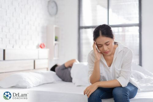 An image of a depressed woman sitting on her bed
