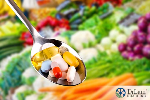An image of supplements in a spoon with various vegetables in the background