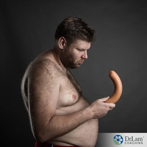 An image of an overweight man staring at a hotdog