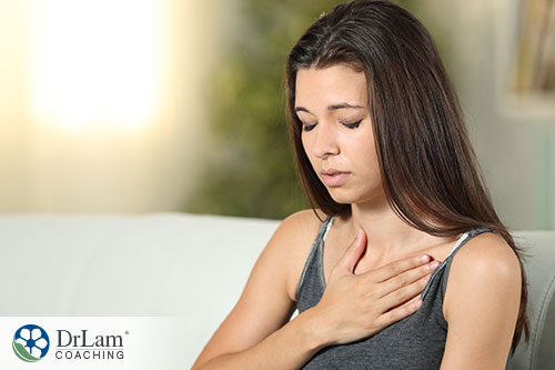 An image of a young woman holding her chest trying to calm down