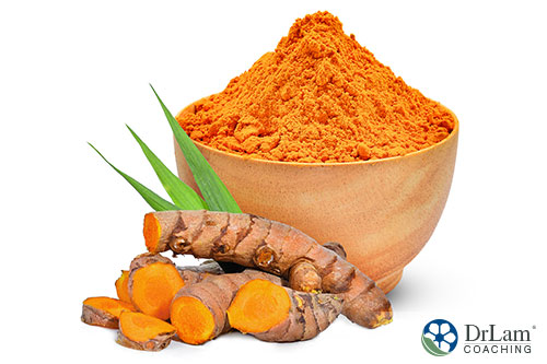 An image of a bowl of turmeric powder with a few turmeric roots next to it
