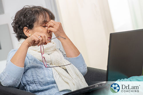 An image of a woman pinching the bridge of her nose while on the computer