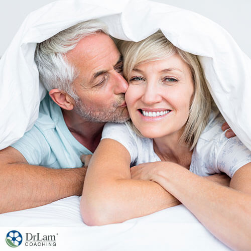 An image of an older couple kissing under the blanket