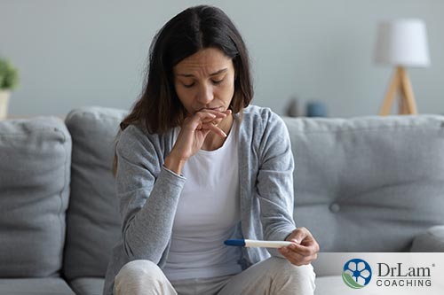 An image of a worried woman holding a pregnancy test strip