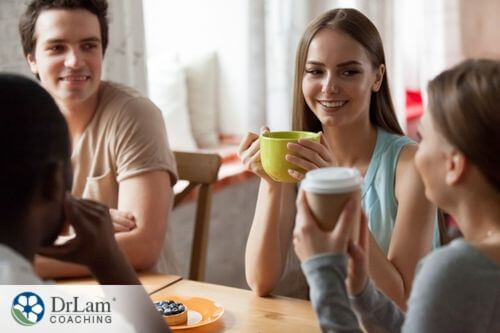 An image of a group of people talking and smiling with coffee in their hands