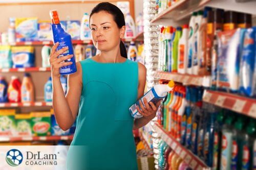 An image of a woman checking the lables of cleaning products for any environmental toxins