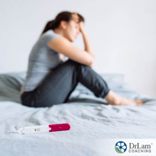 An image of a woman sitting on the bed with a negative pregnancy test