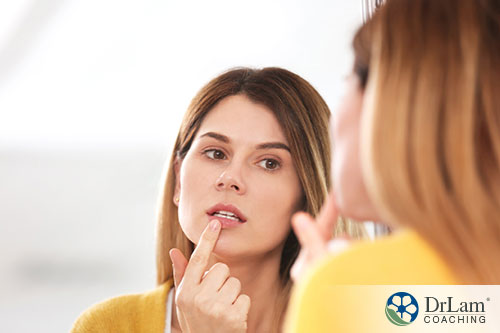 an image of a young woman looking at her lip in the mirror
